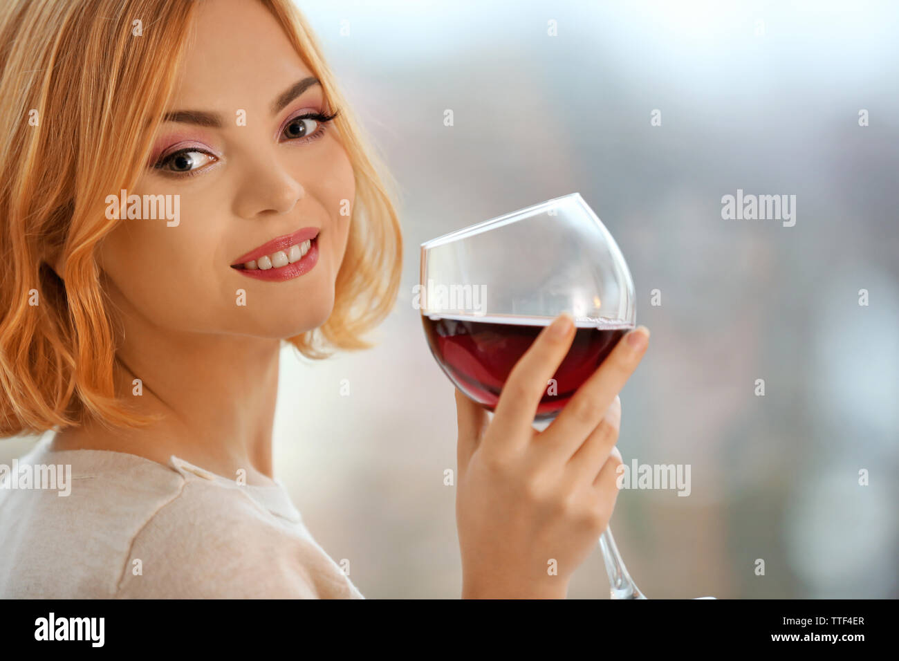 Young woman with glass of red wine on light blurred background Stock ...