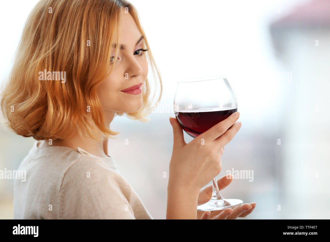 Young woman with glass of red wine on light blurred background Stock ...