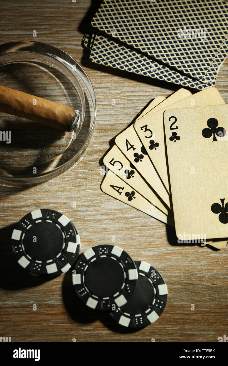 Set to playing poker with cards and chips on wooden table, top view
