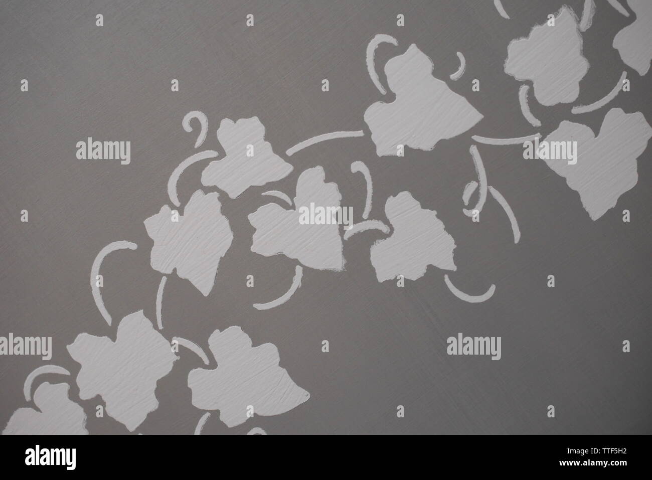 Stencil of vine leaves on a grey chalk painted table top Stock Photo