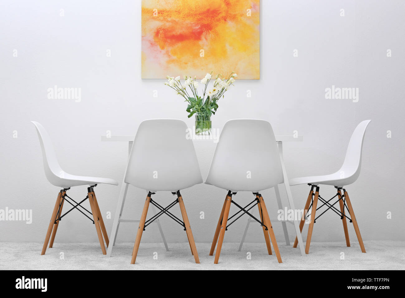 Modern dining room. White chairs and table with bouquet of flowers ...