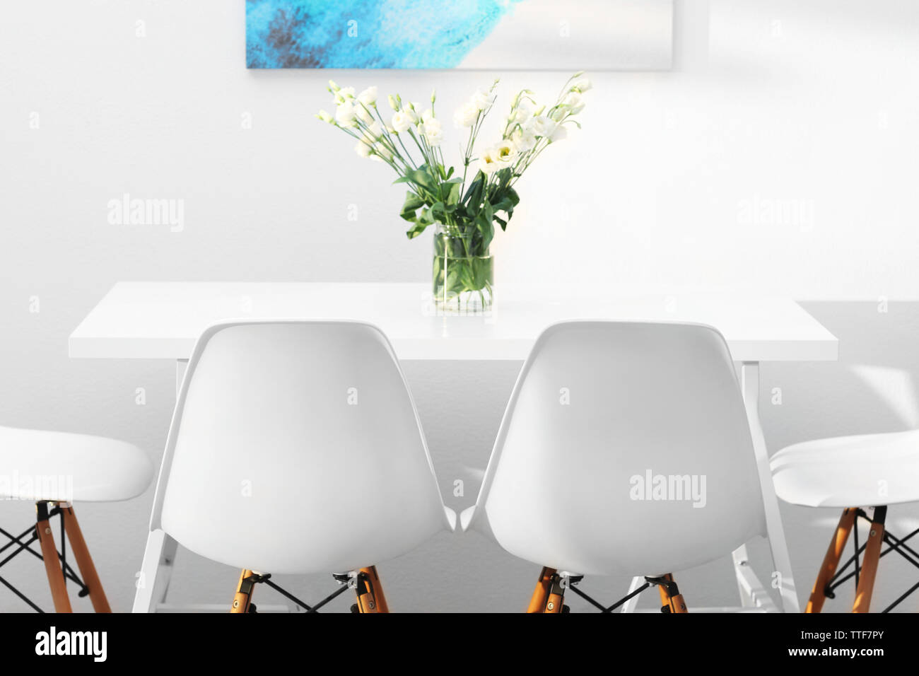 Modern dining room. White chairs and table with bouquet of flowers ...