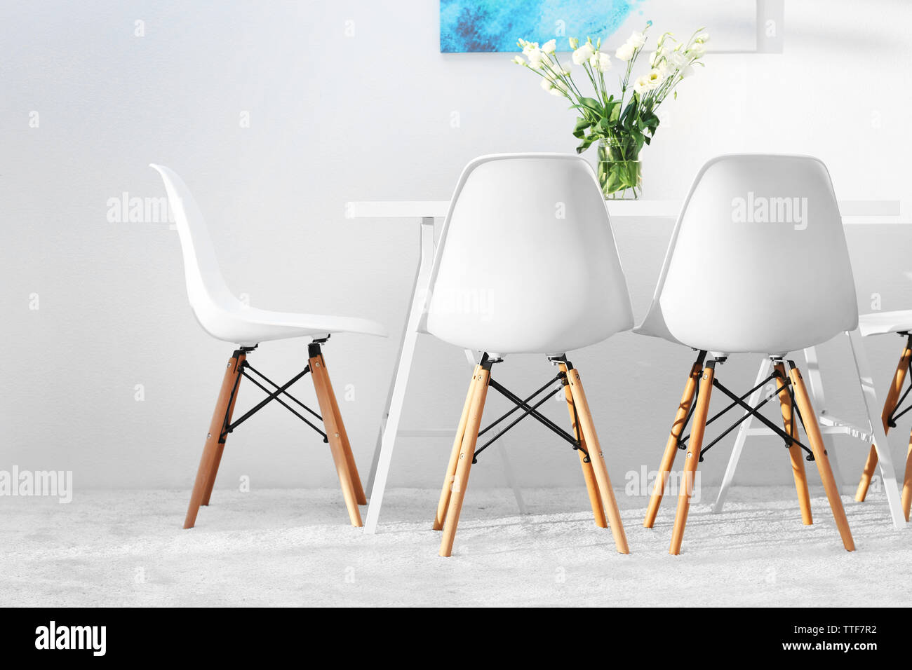 Modern dining room. White chairs and table with bouquet of flowers ...