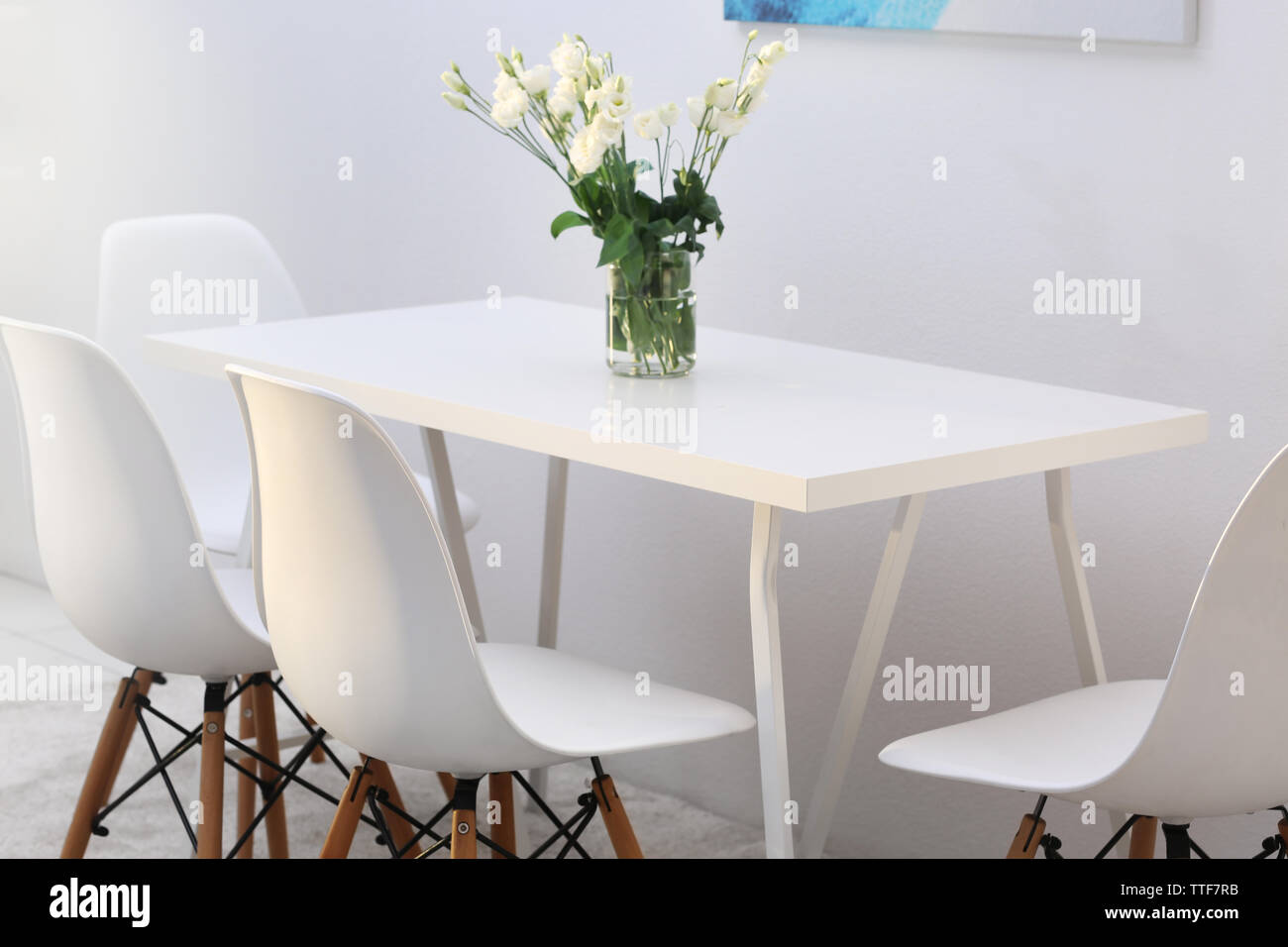 Modern dining room. White chairs and table with bouquet of flowers ...