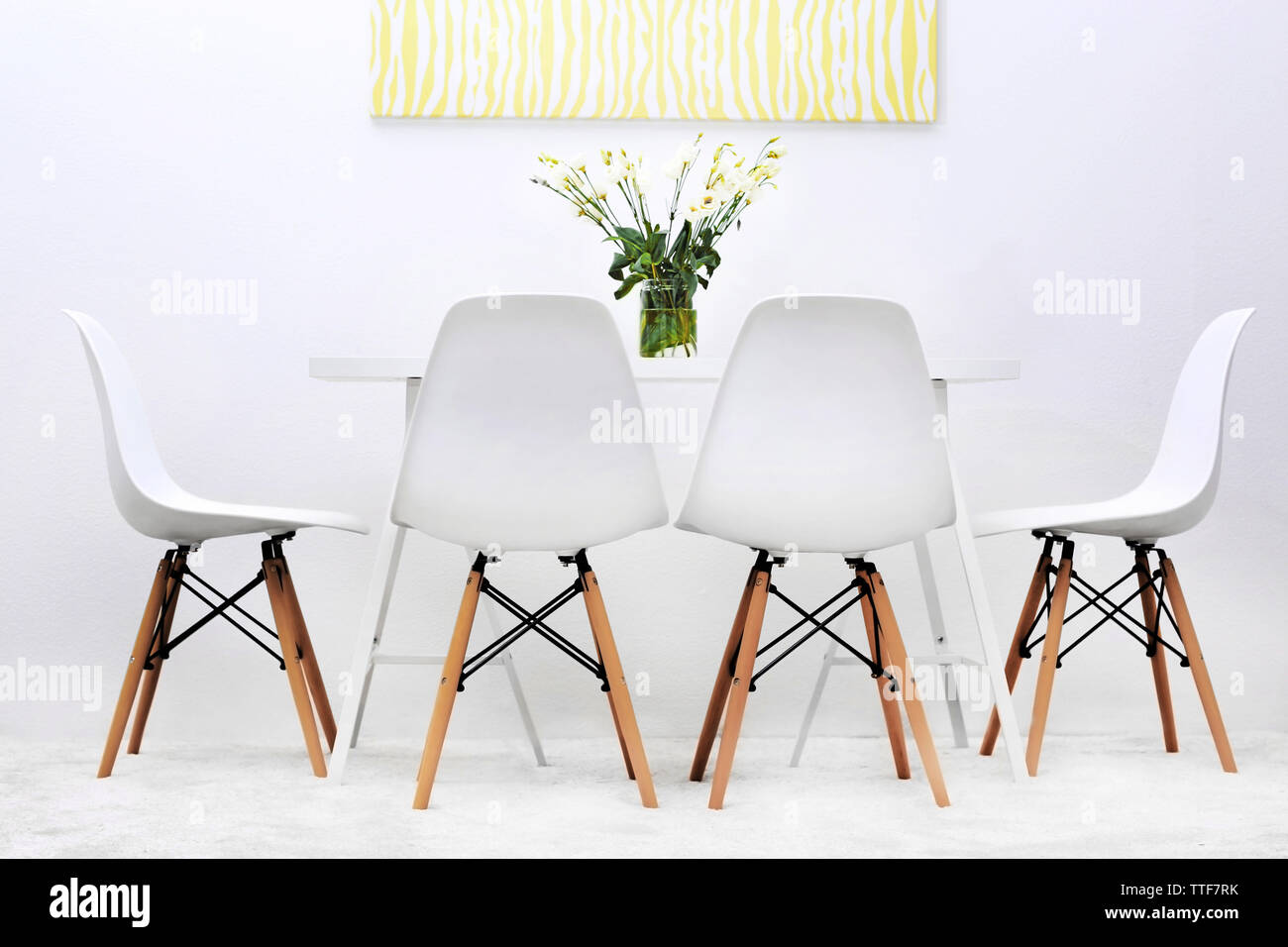 Modern dining room. White chairs and table with bouquet of flowers ...