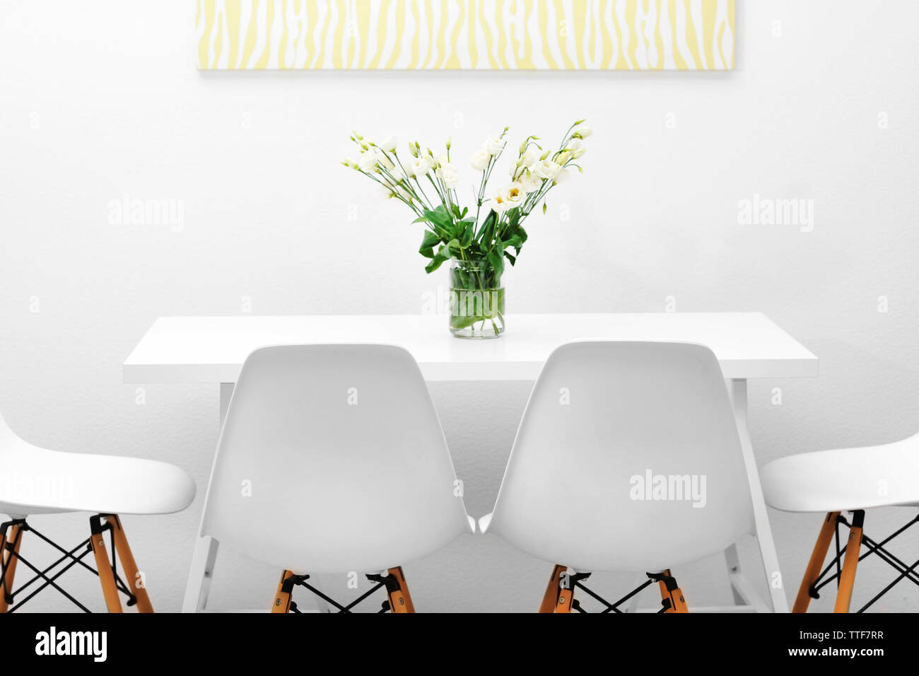 Modern dining room. White chairs and table with bouquet of flowers ...