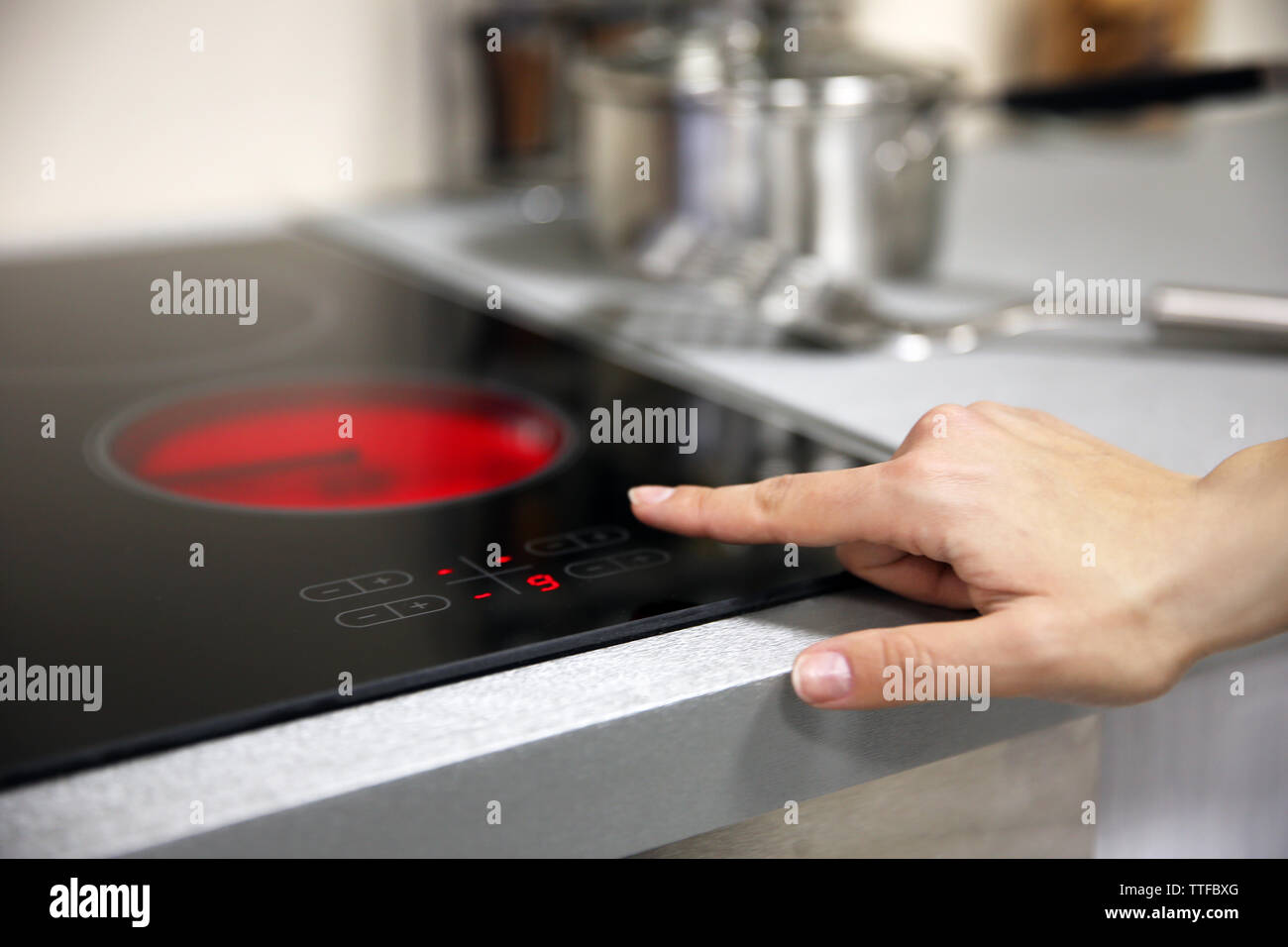 Female hand turns on electric hob closeup Stock Photo Alamy