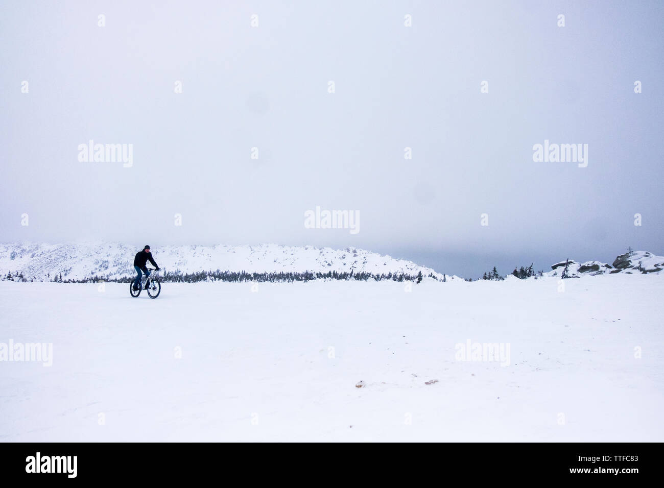 Man riding bicycle on snow covered field Stock Photo
