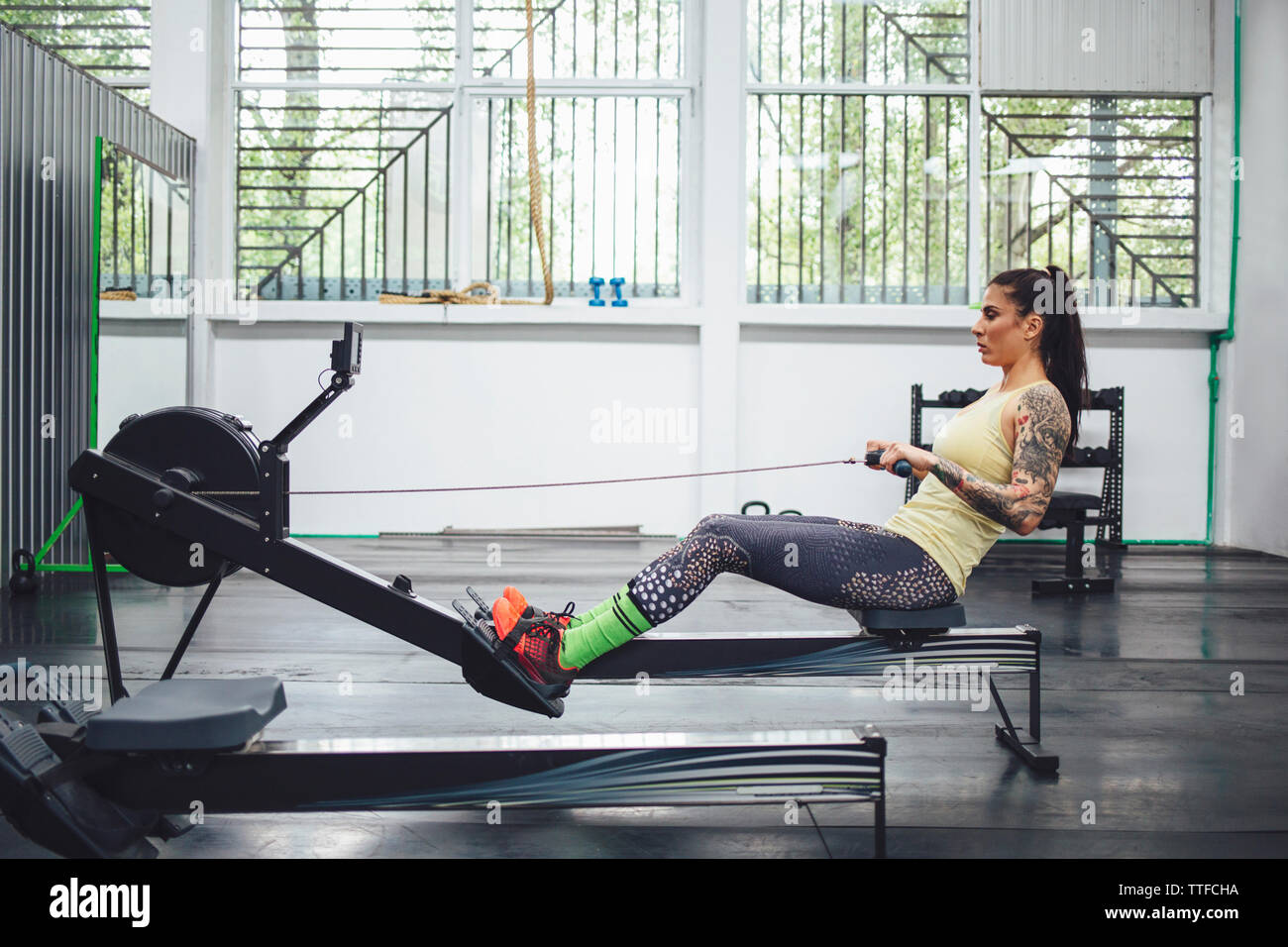 Athlete using rowing machine in gym Stock Photo
