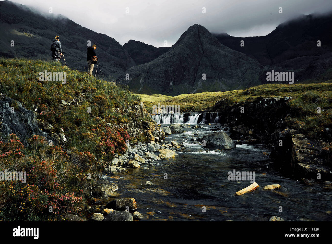 Fery gleen.Two photographs stand at the waterfall against the backdrop Stock Photo