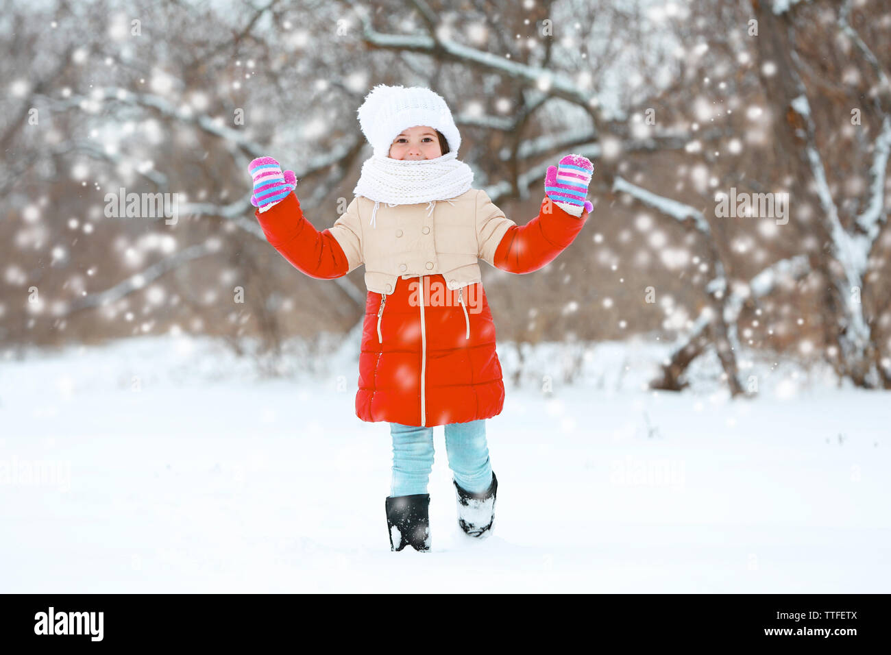 Little girl with winter clothes going through deep snow in park