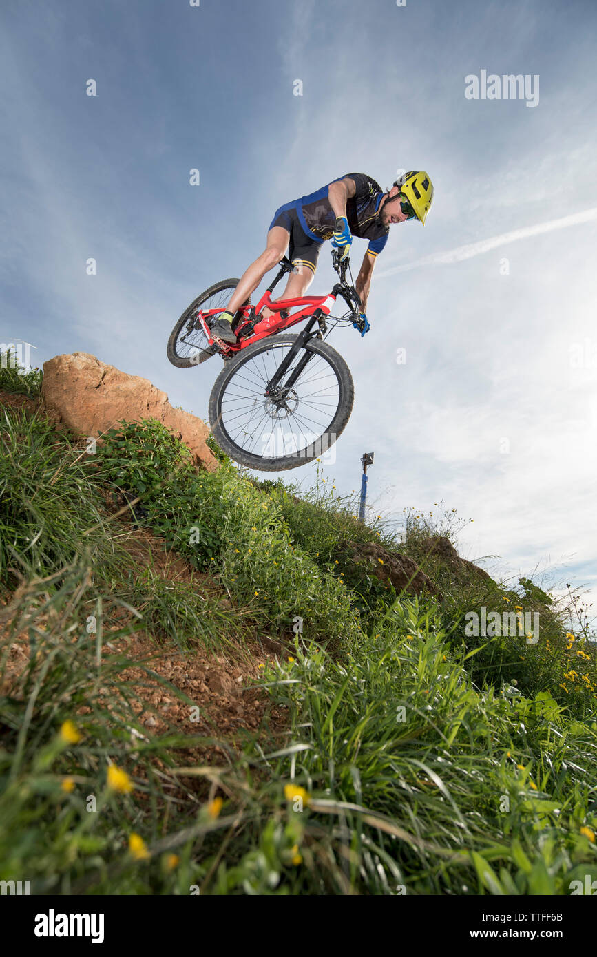 Mountain biker jumping downhill on his bike over grass Stock Photo