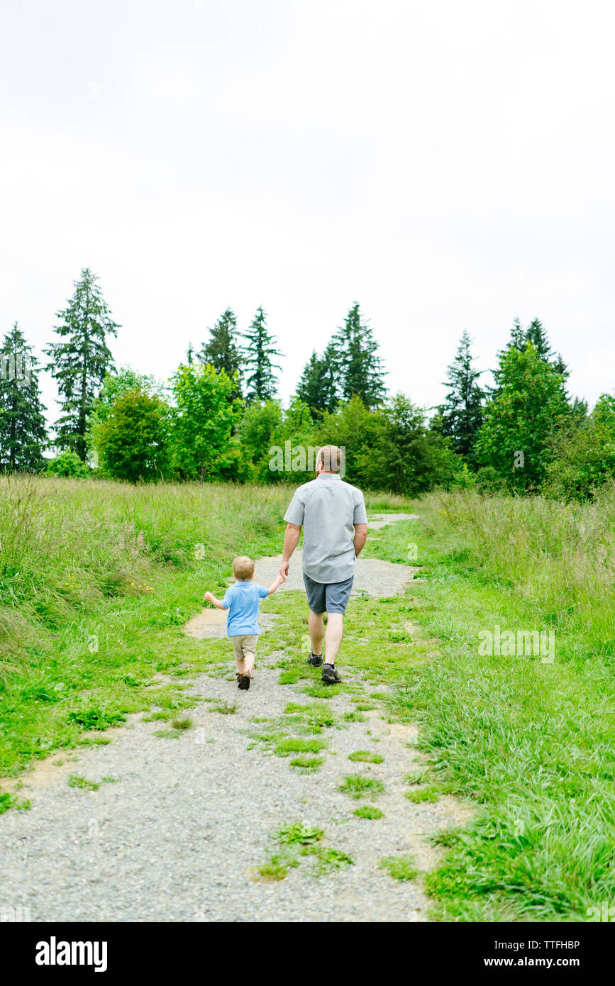 Rear view of a father and son walking down a path Stock Photo - Alamy