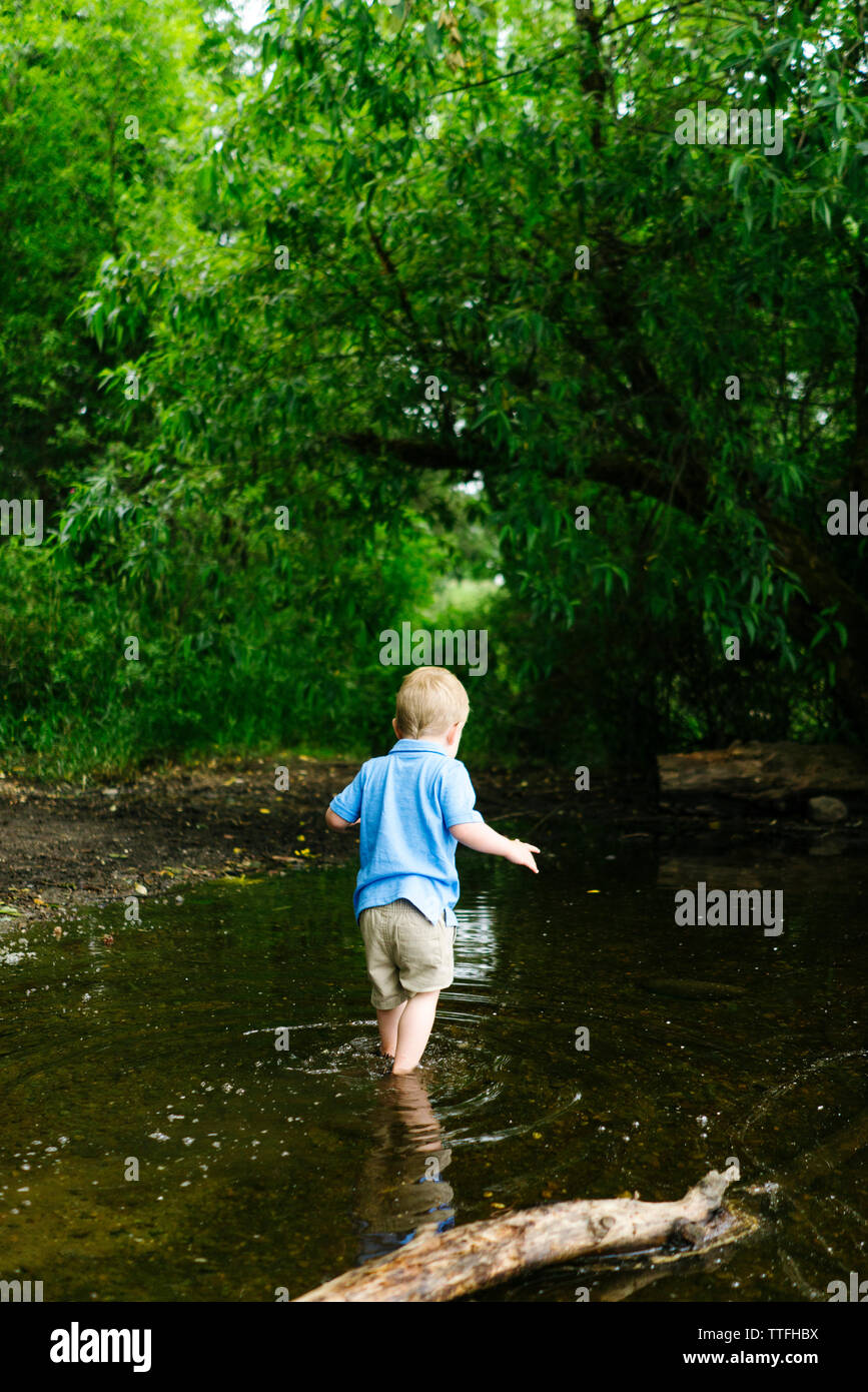 Rear view of a young boy playing on the edge of a lake Stock Photo