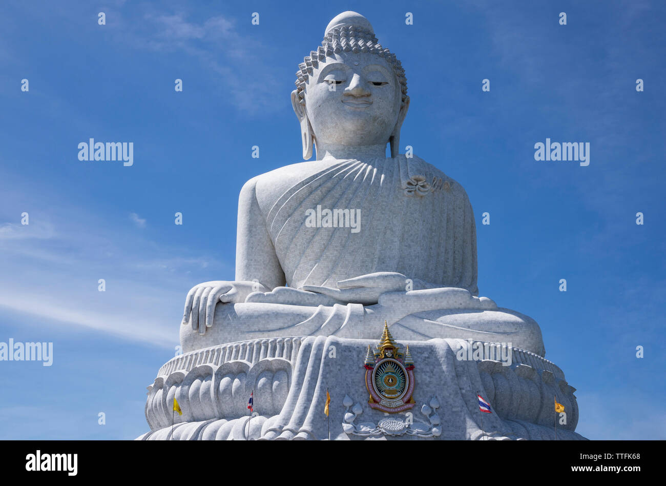 Low angle view of Buddha statue against blue sky during sunny day Stock Photo