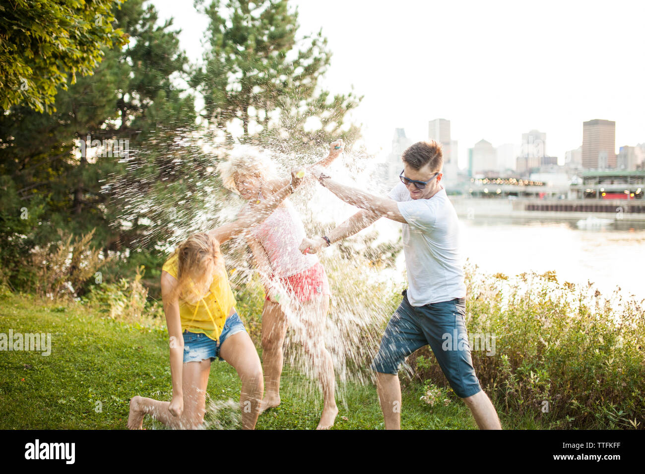 Friends throwing water balloons at eachother laughing hysterically Stock Photo