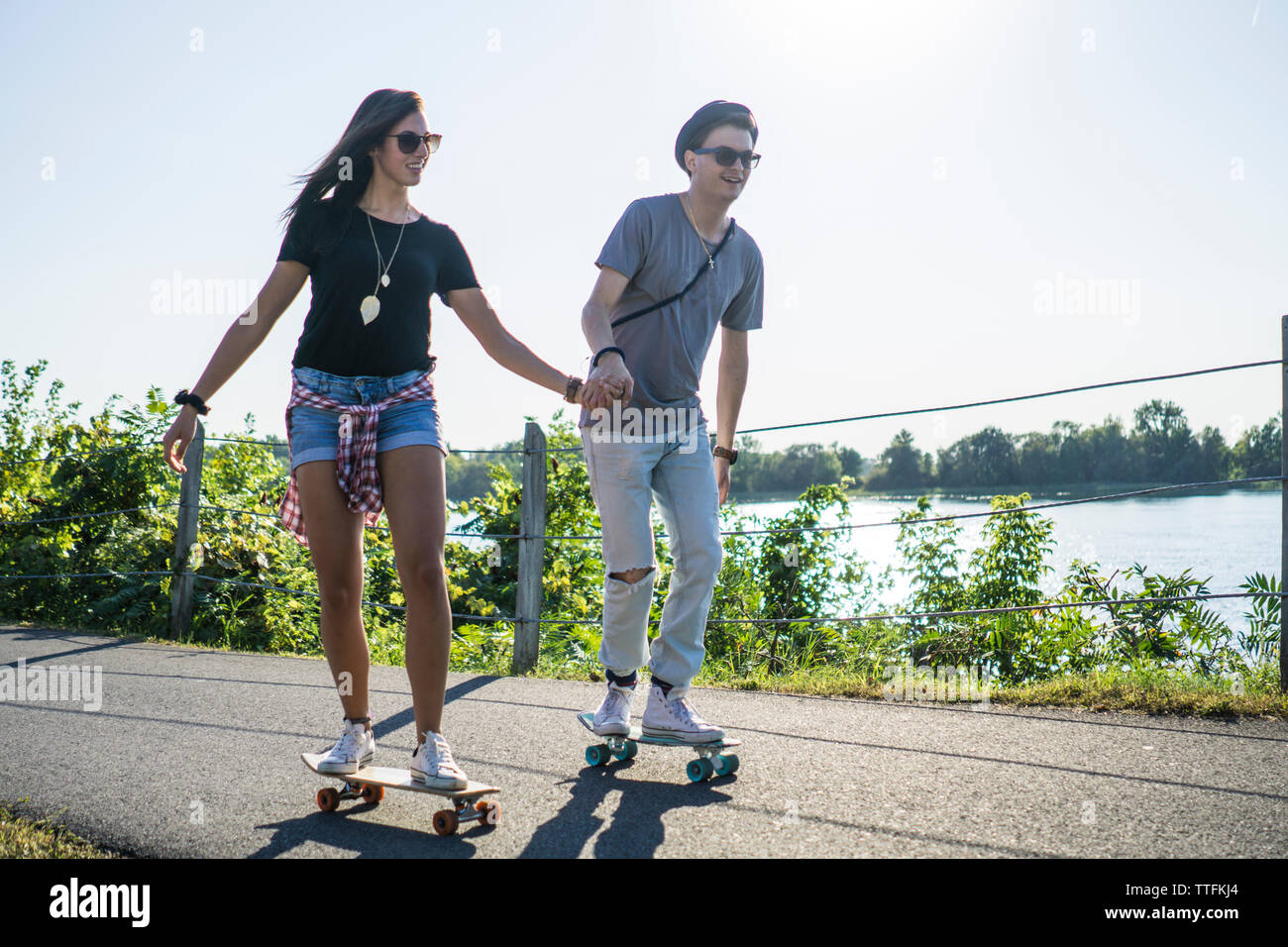 Couple cruising down bike path together on skateboard cruiser boards Stock Photo