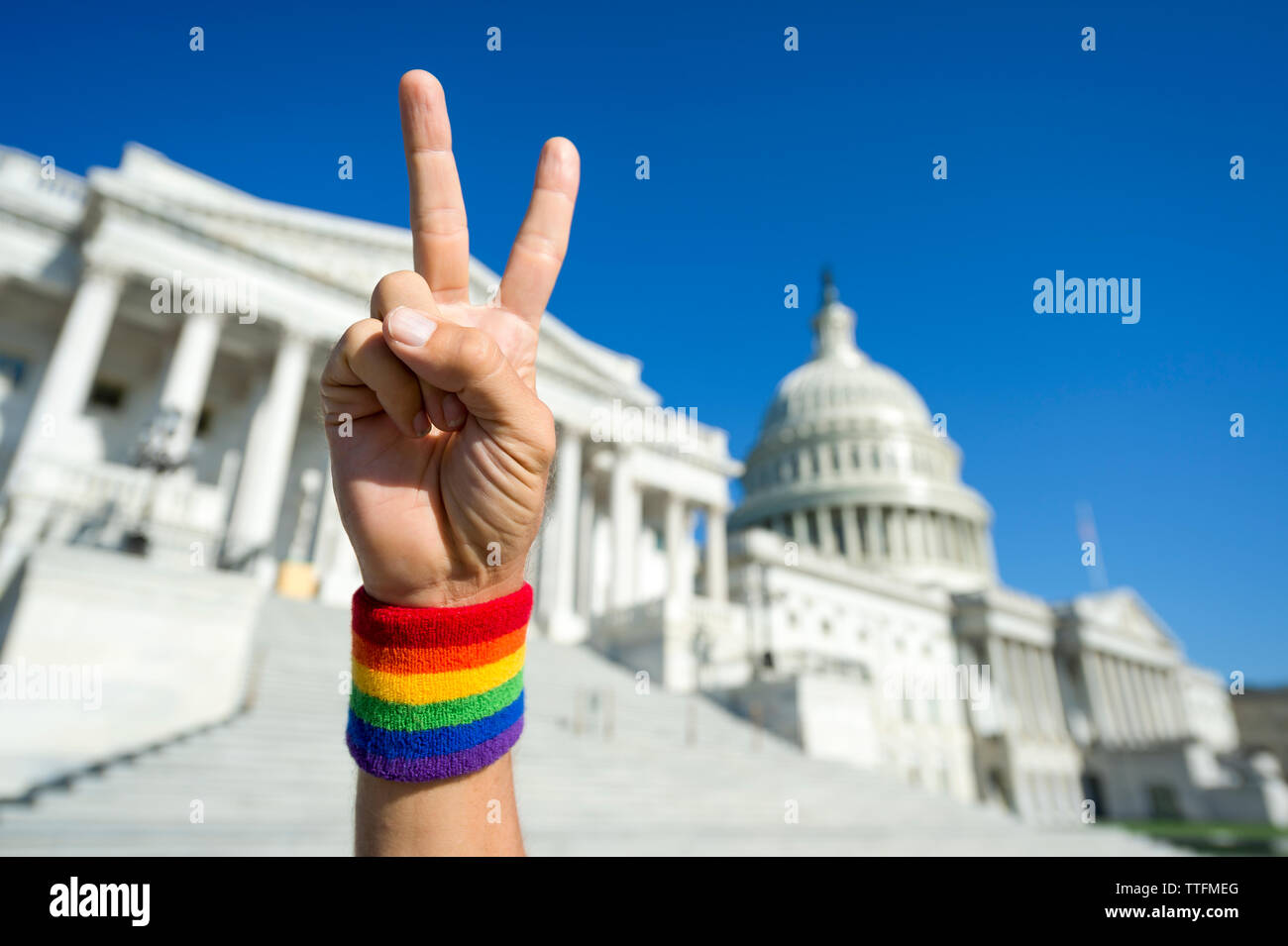 Hand with gay pride rainbow wristband making a peace sign in front of the Capitol Building in Washington, DC, USA Stock Photo