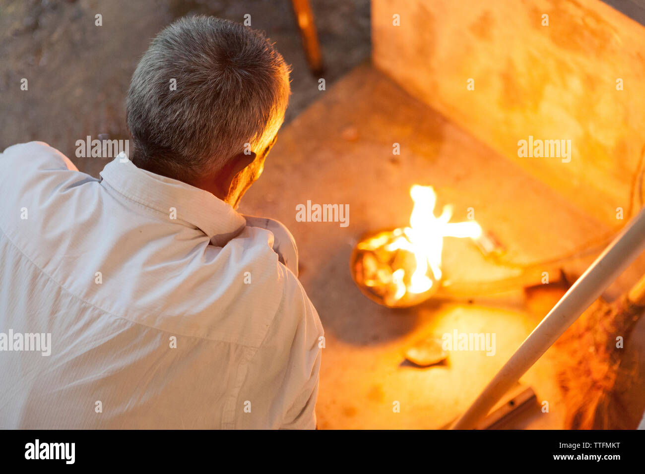 Old man in front of a small fire, Sri Lanka Stock Photo