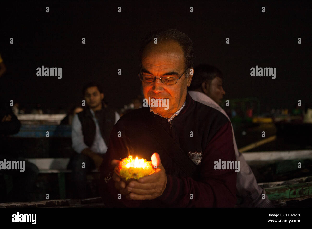 Caucasian 60 years old man at night holding a candle in India Stock Photo