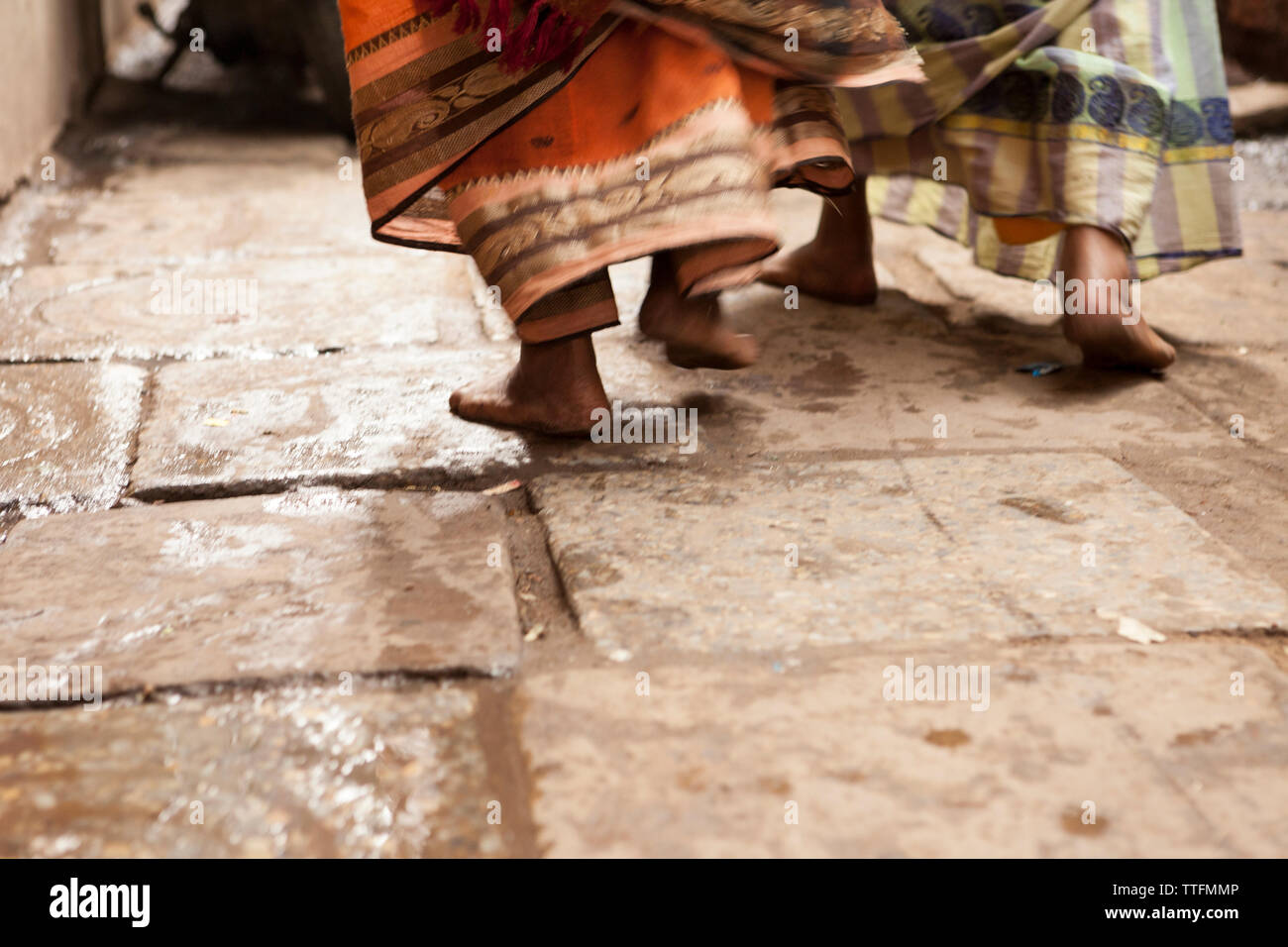 close up of women feet walking barefoot with traditional saris TTFMMP