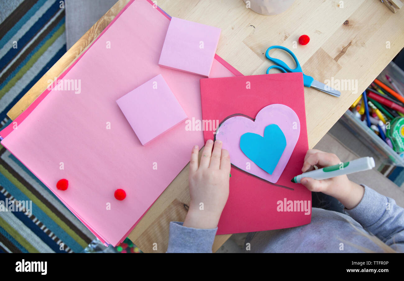 Midsection of girl making Valentine card at home Stock Photo