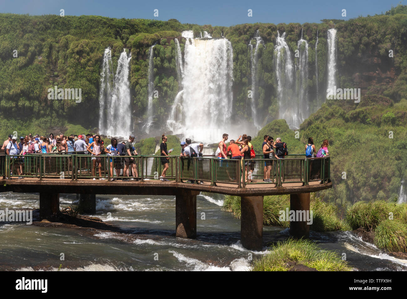 Beautiful landscape of tourists on footbridge visiting big waterfalls Stock Photo