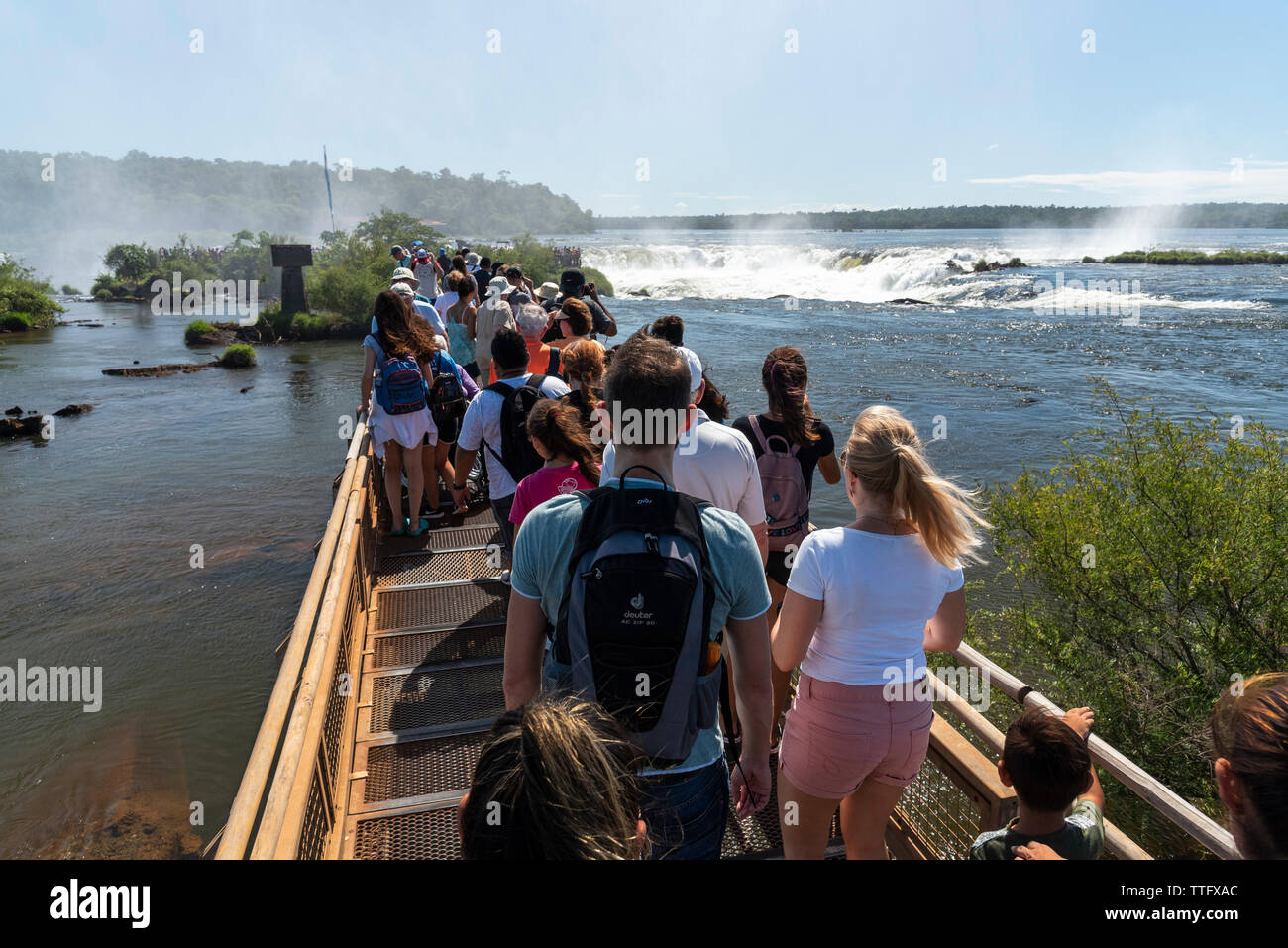 Tourists over footbridge visiting big waterfalls on the rainforest Stock Photo
