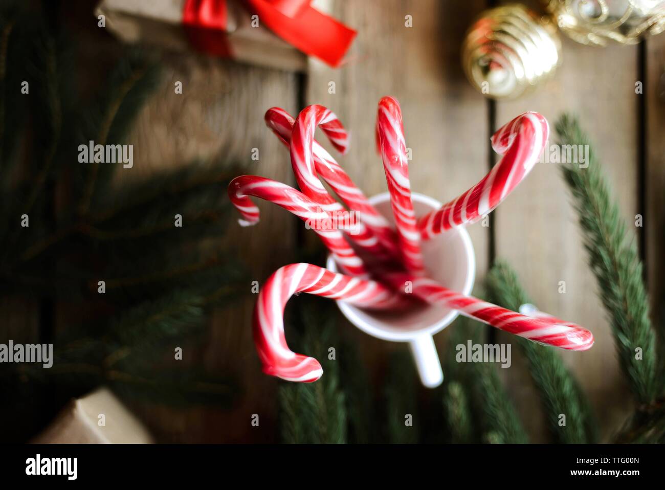Close-up of candy canes in cup by baubles and twig on wooden table Stock Photo