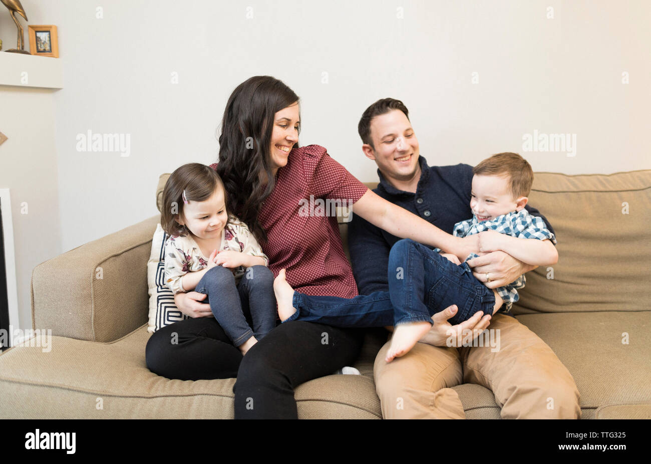 Playful family sitting on sofa at home Stock Photo