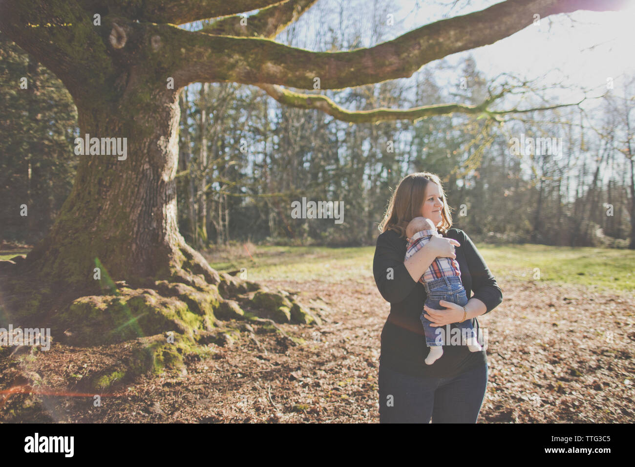 Mother holding her son outdoors at nature park. Stock Photo