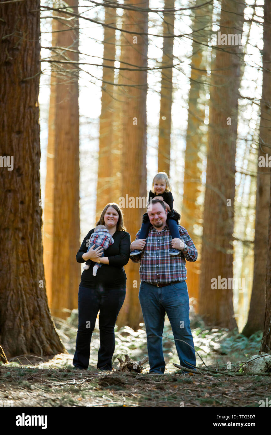 Happy family of four smiling in forest setting. Stock Photo