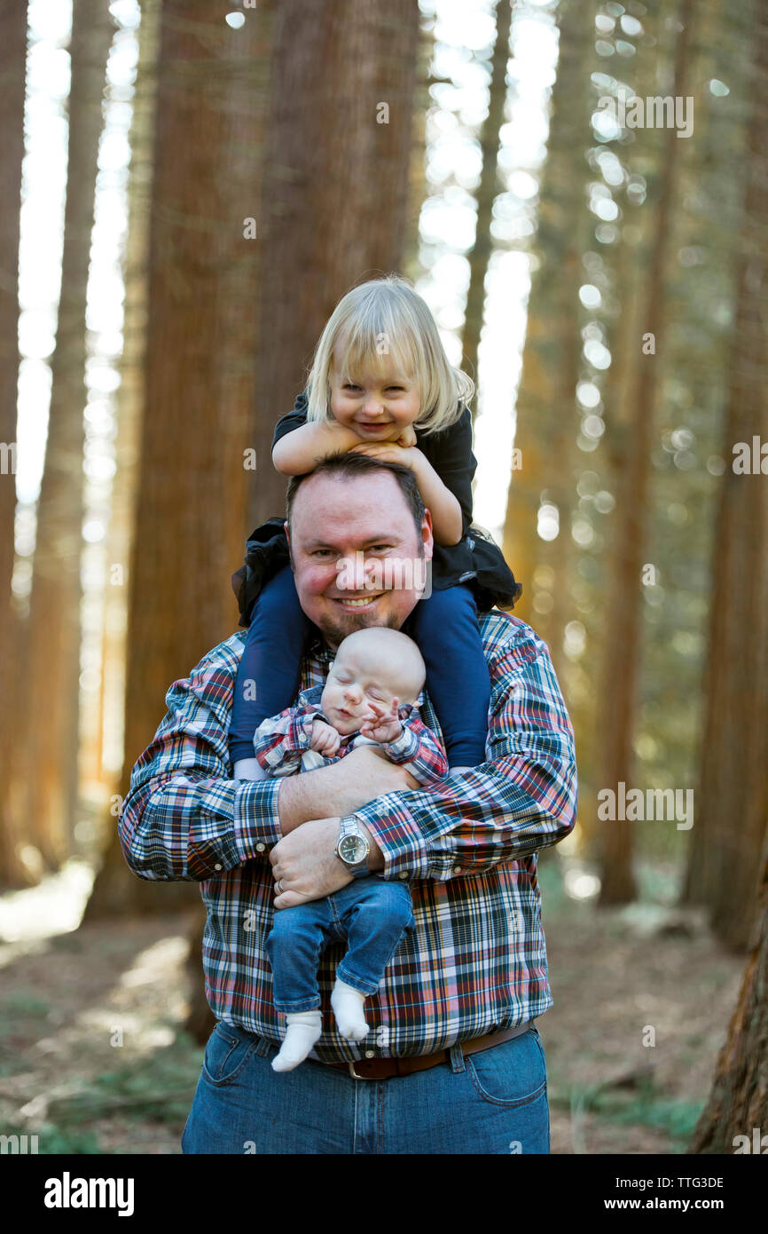 Father holds his daughter and young son in a forest setting. Stock Photo