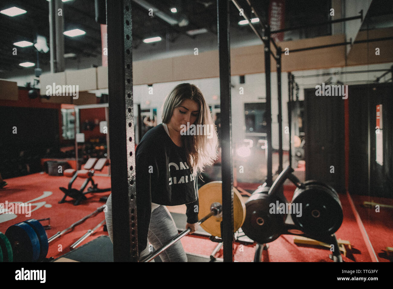 fit, attractive female working out using a barbell and squat rack Stock Photo