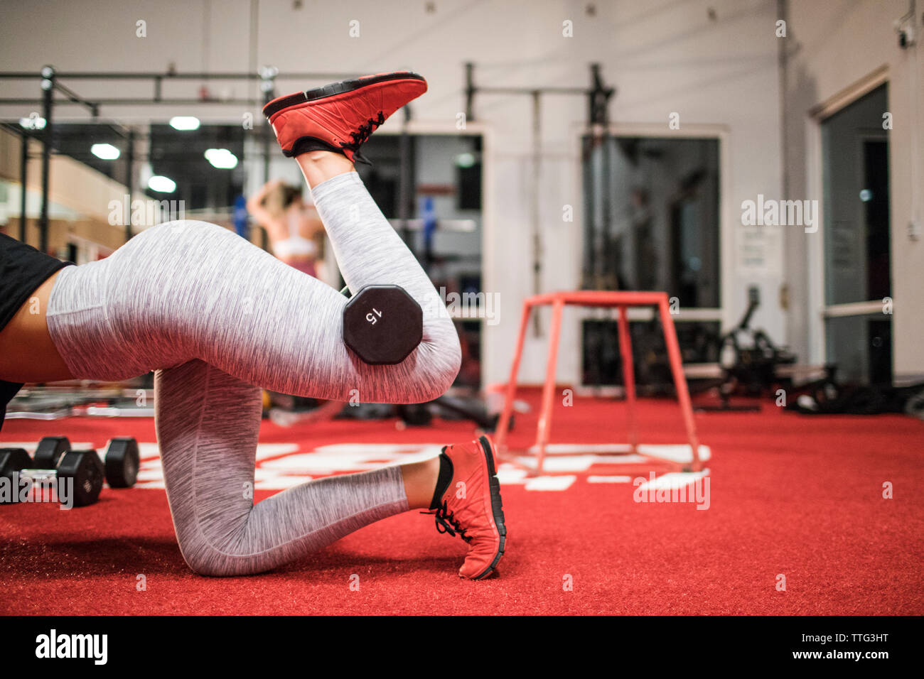 Woman lifts a dumbbell with her leg at the gym. Stock Photo