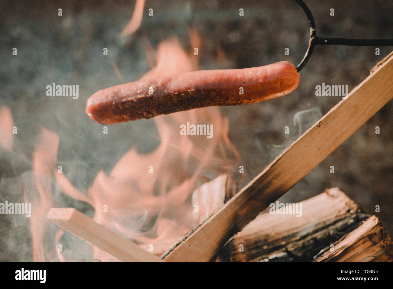 Hot dog cooking over campfire Stock Photo