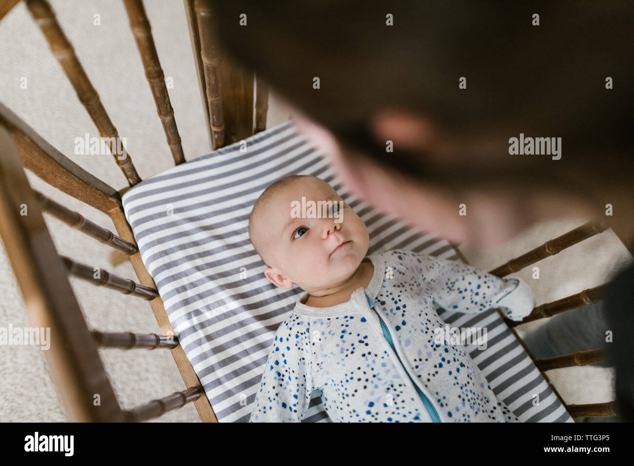 Mother looking down on baby laying in crib after nap. Stock Photo