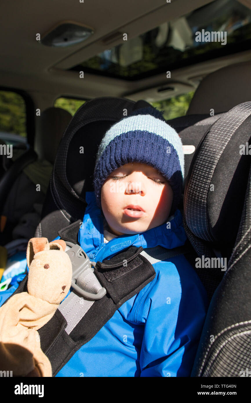 Toddler boy sleeping in his car seat during a road trip. Stock Photo