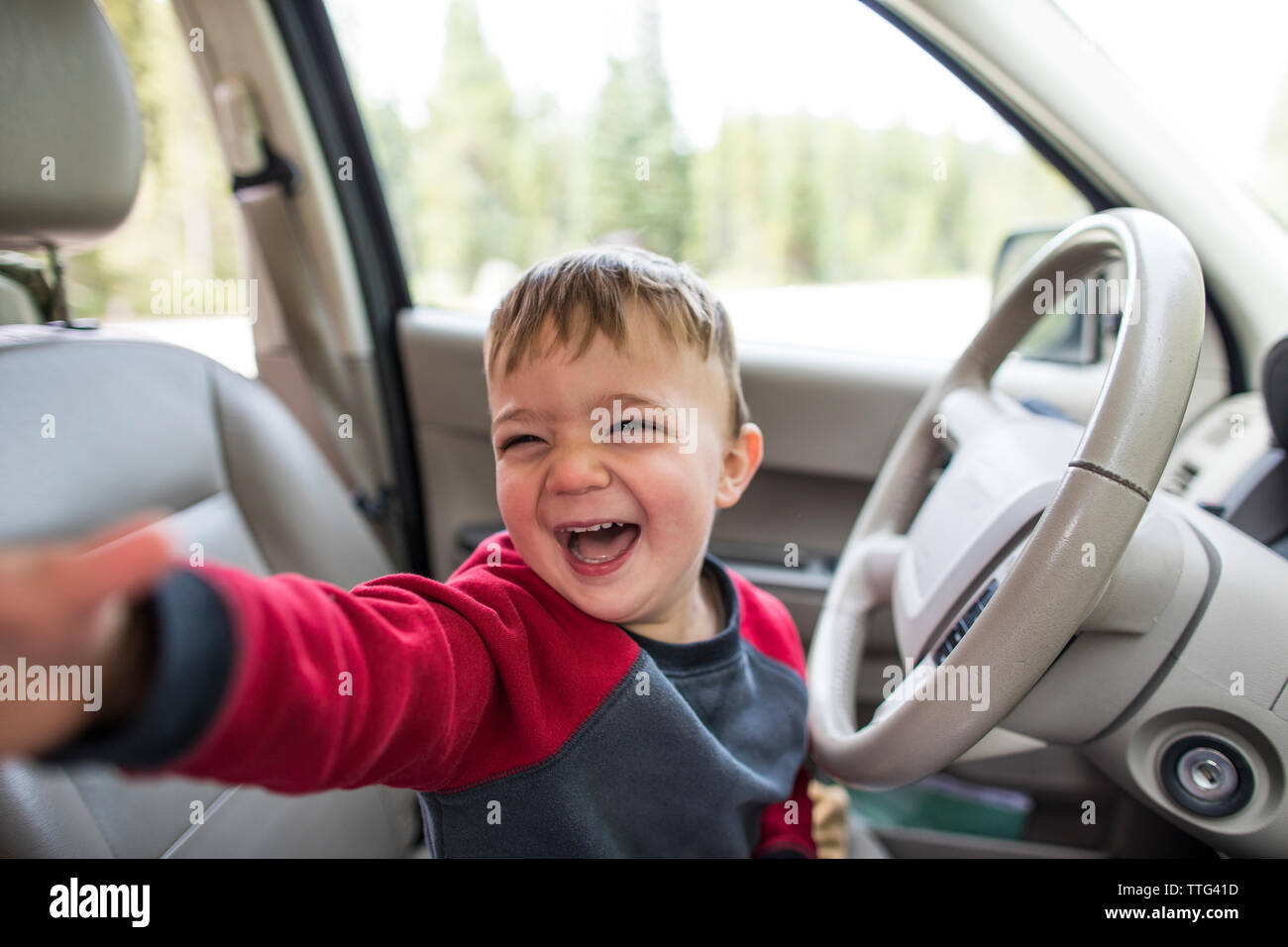 Happy little boy sitting on driver's seat in a car Stock Photo