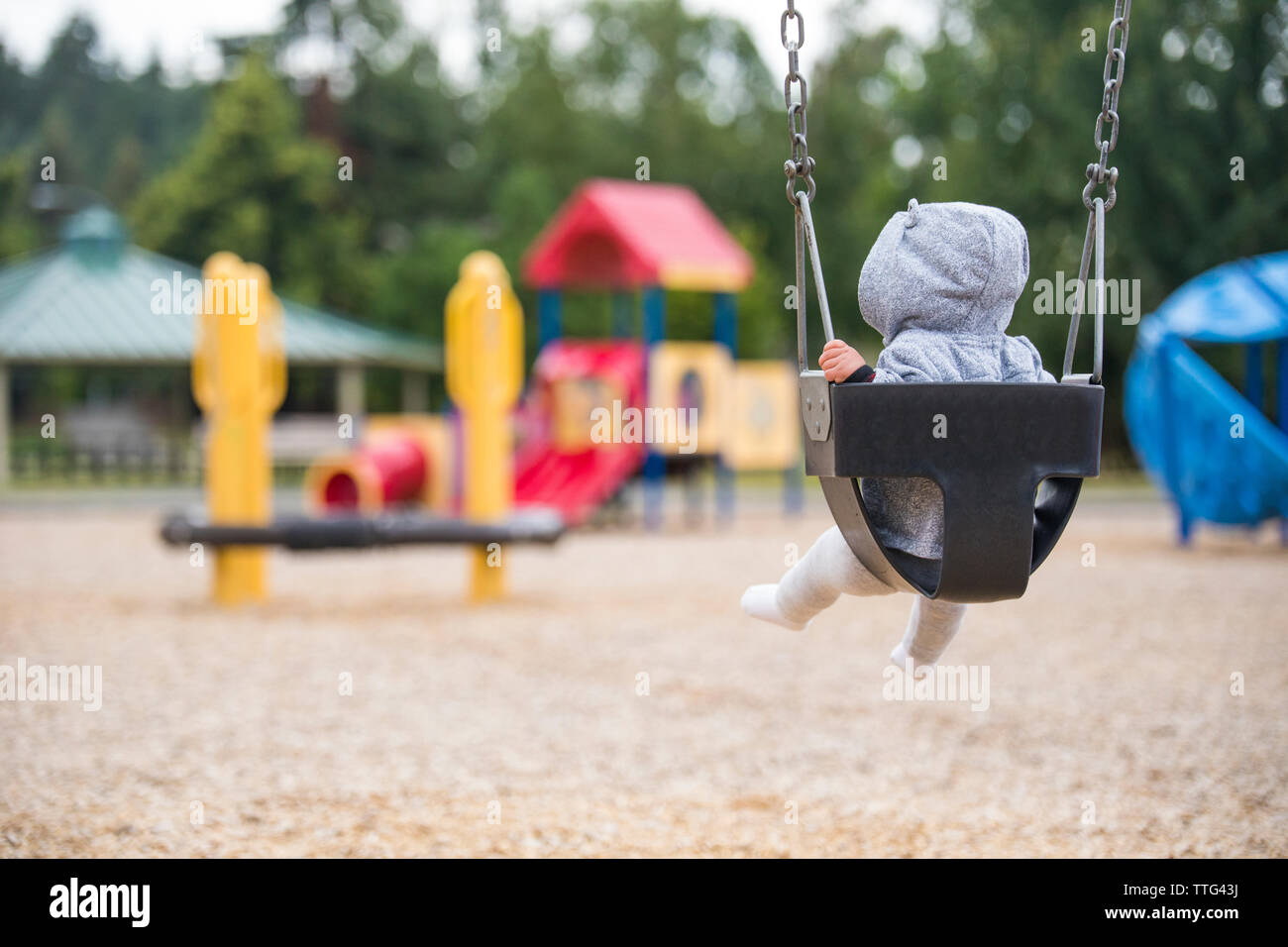 Rear view of baby girl sitting on swing at park Stock Photo