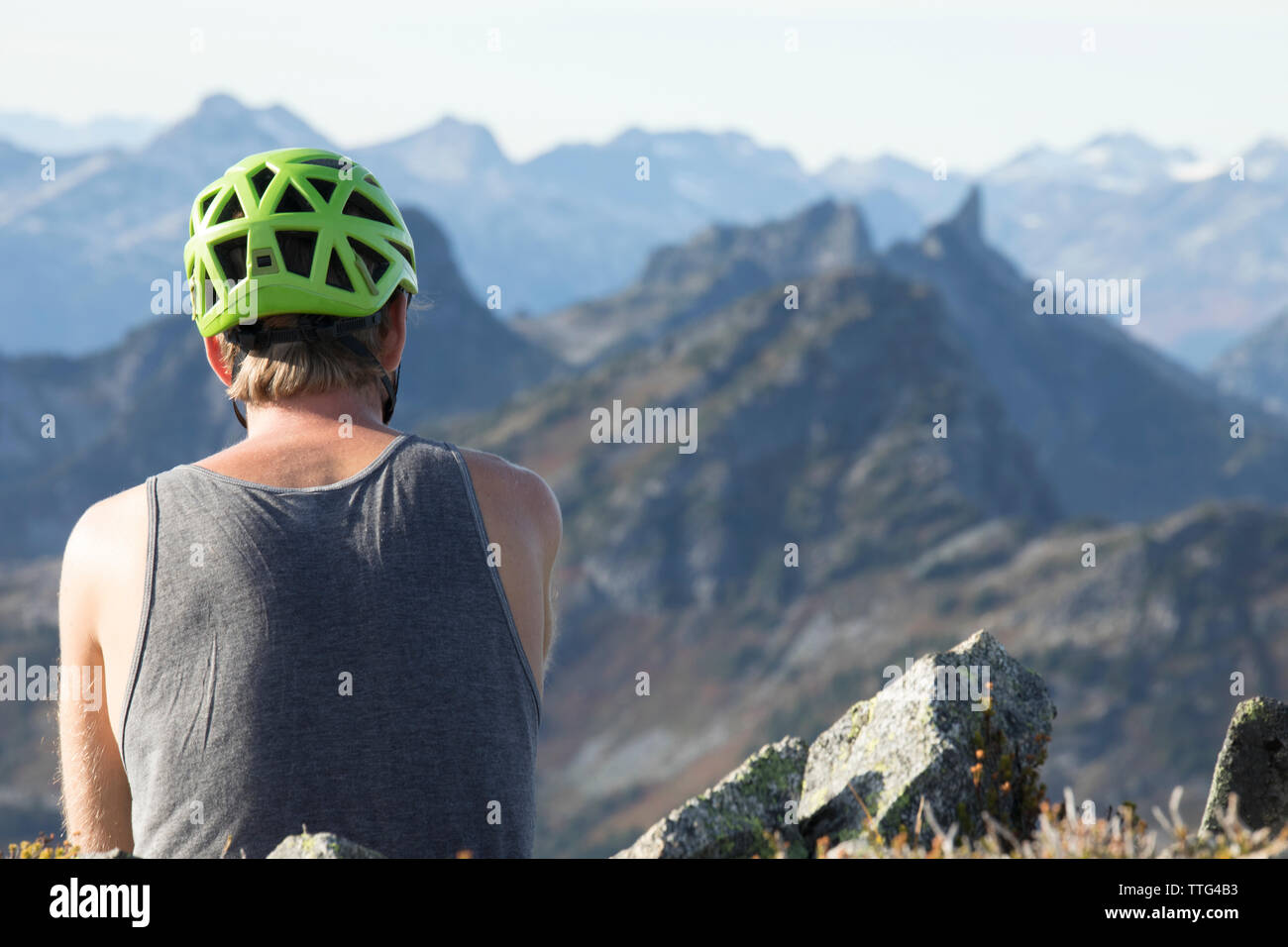 rear view of climber enjoying moment of solitude on mountain summit. Stock Photo
