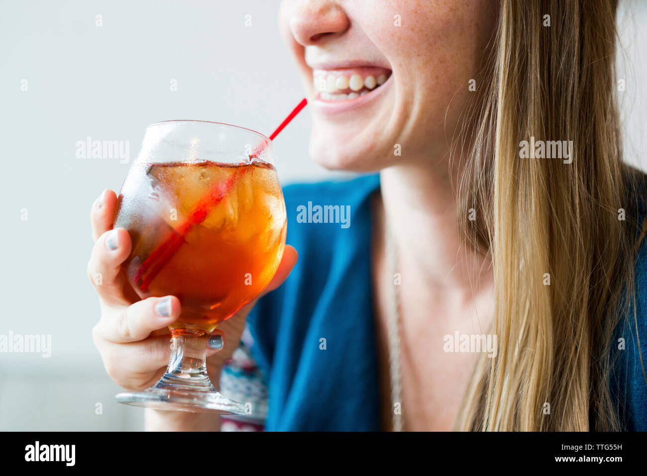 Midsection of smiling woman enjoying ice tea in cafe Stock Photo
