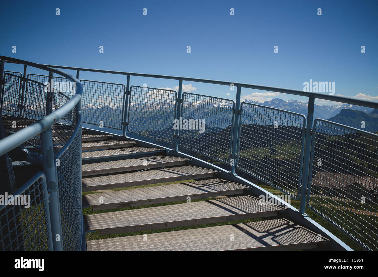 an outdoor spiral staircase with mountains in the background Stock Photo