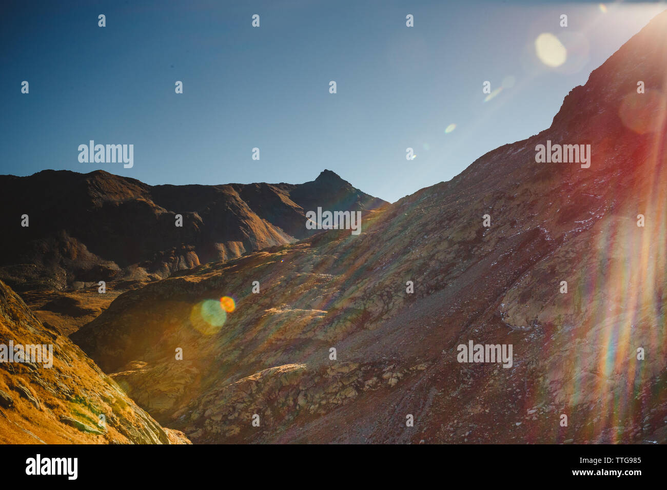 A rugged mountain ridge with a rainbow sunflare Stock Photo