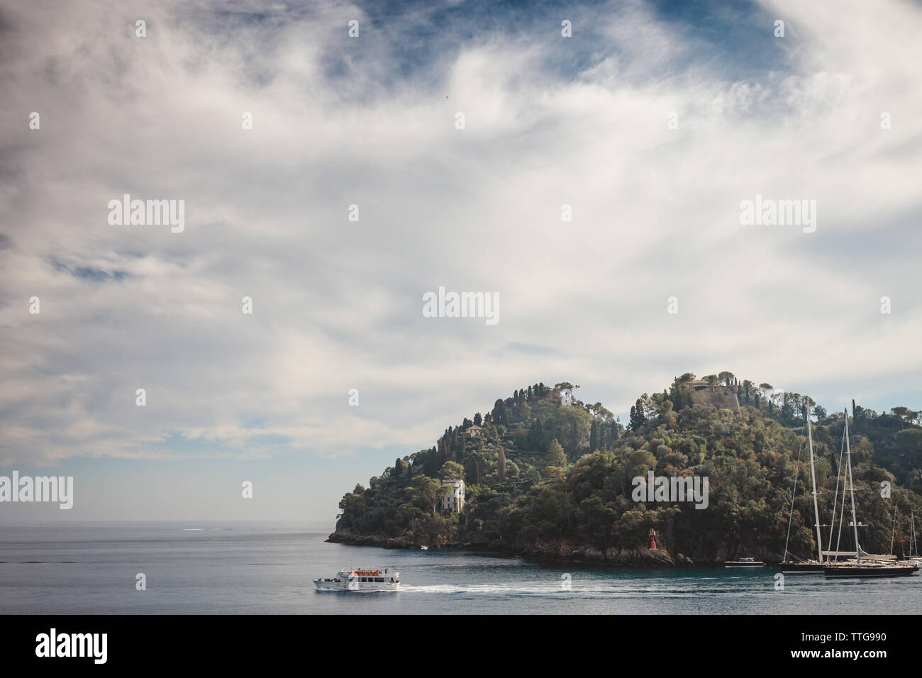 A tourboat departs from a bay under a dramatic sky Stock Photo