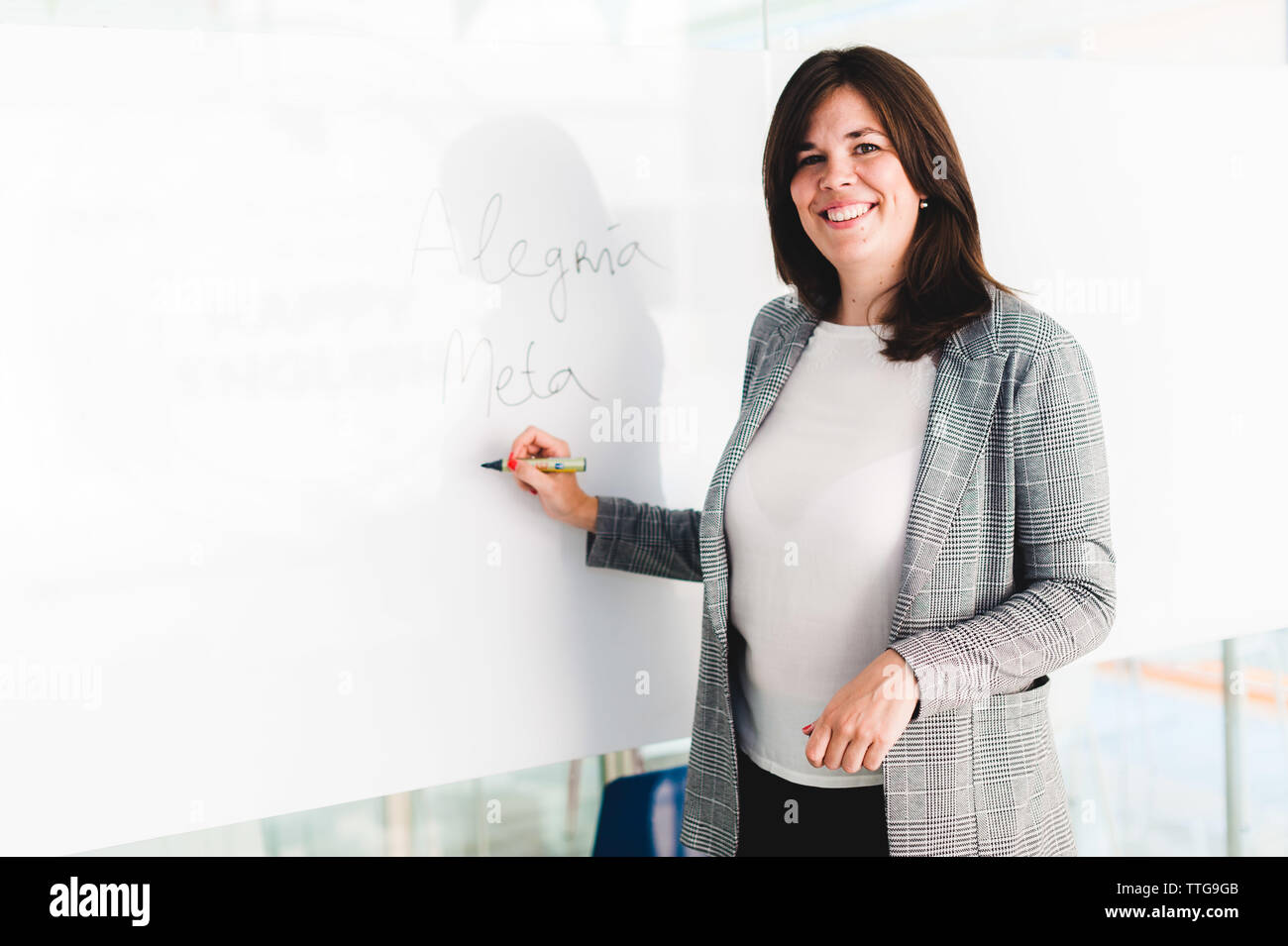 Teacher Smiling and Writing on Whiteboard Stock Photo