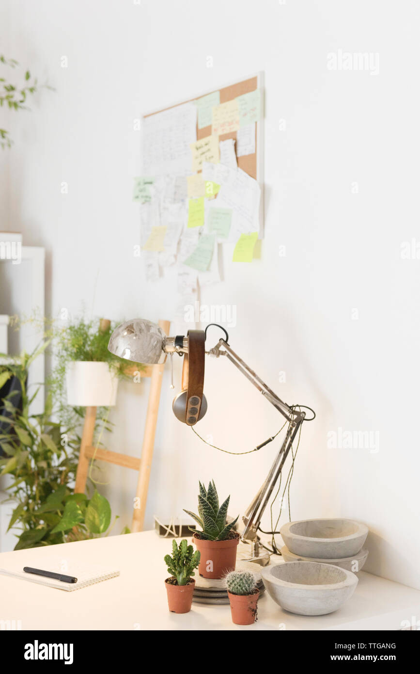 Headphones on desk lamp by houseplants on desk in creative office Stock Photo