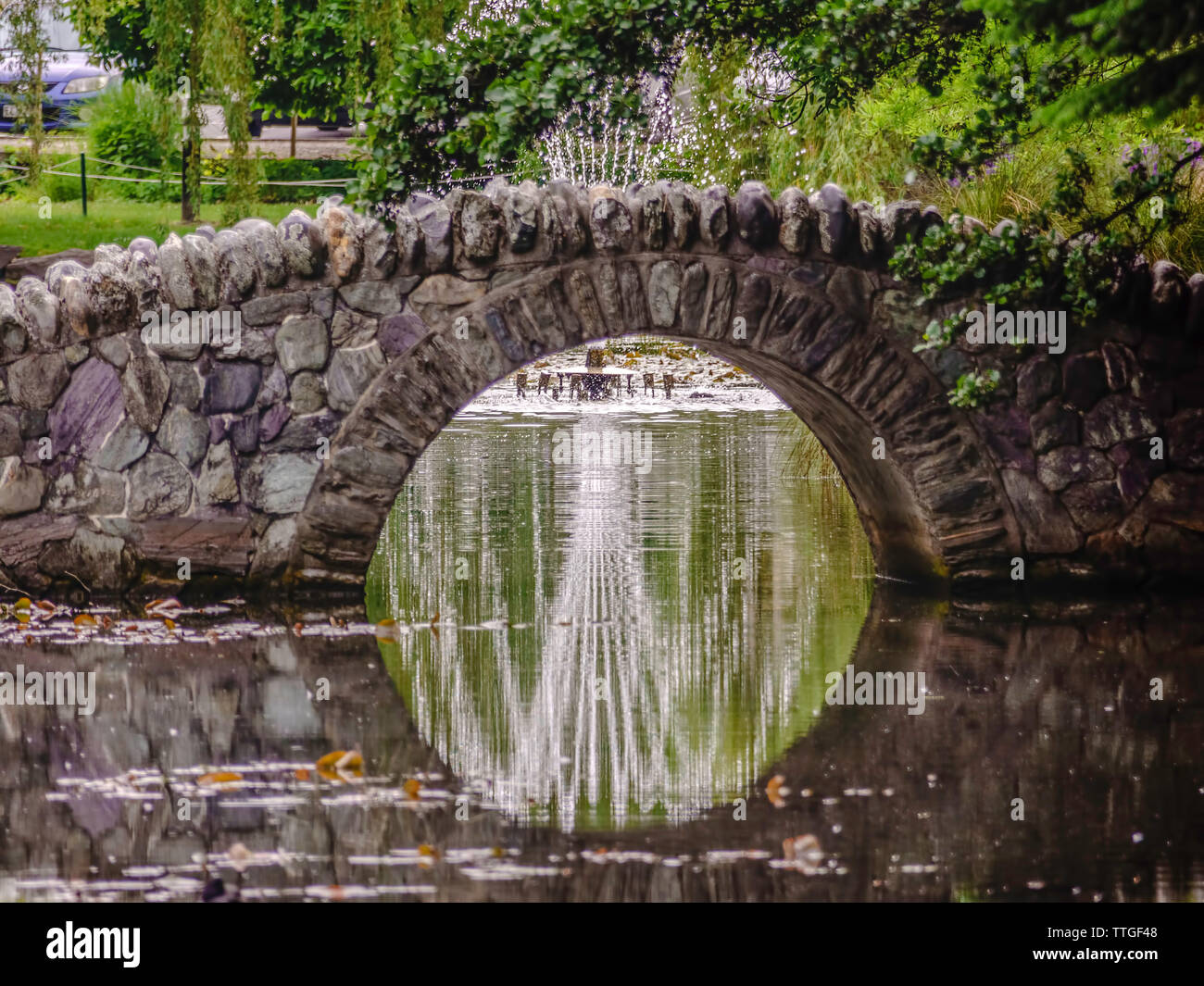Fountain reflected on pond under footbridge in Queenstown, New Zealand Stock Photo