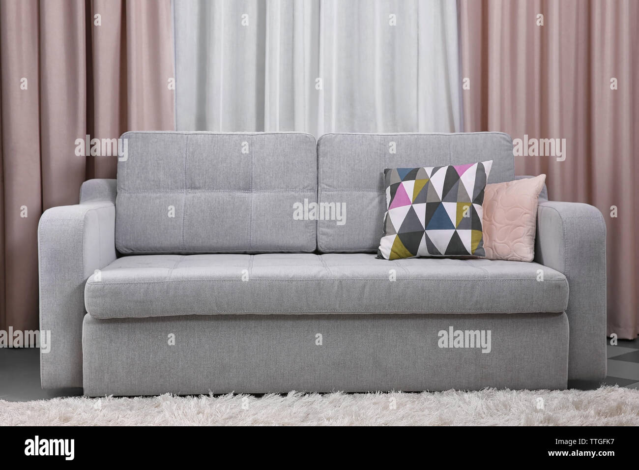Grey sofa against curtains in the room Stock Photo - Alamy