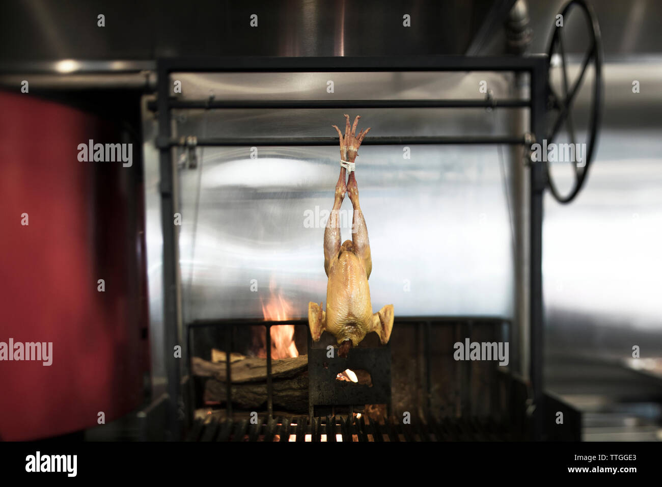 Chicken meat hanging over barbecue grill Stock Photo